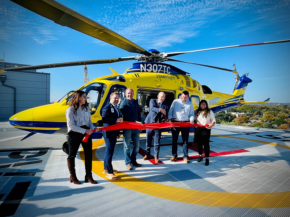 GC Specialty Construction - Ascension Seton Medical Center Helipad Relocation - The Beck Group a photo of a helicopter with people cutting a ribbon in front of it